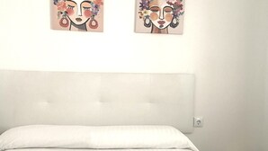 Une chambre à coucher avec un grand lit, une tête de lit et deux œuvres d’art accrochées au mur.