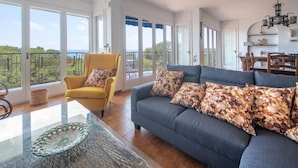 A spacious living room with a sofa, armchair, and dining area.