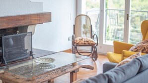 A living room with a glass coffee table, a sofa, a chair, and a fireplace.