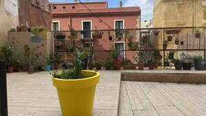 A courtyard with potted plants, a yellow planter, and buildings in the background. - Th146 Apartamento Elegante Cerca de la Catedral (Tarragona)