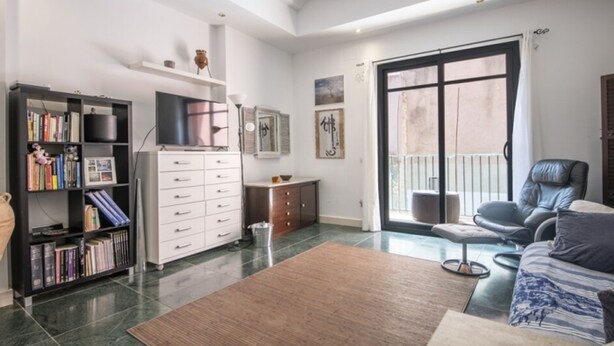 A spacious living room with a large window, a bookshelf, a flat-screen TV, a sofa, and a coffee table. - Th146 Apartamento Elegante Cerca de la Catedral (Tarragona)