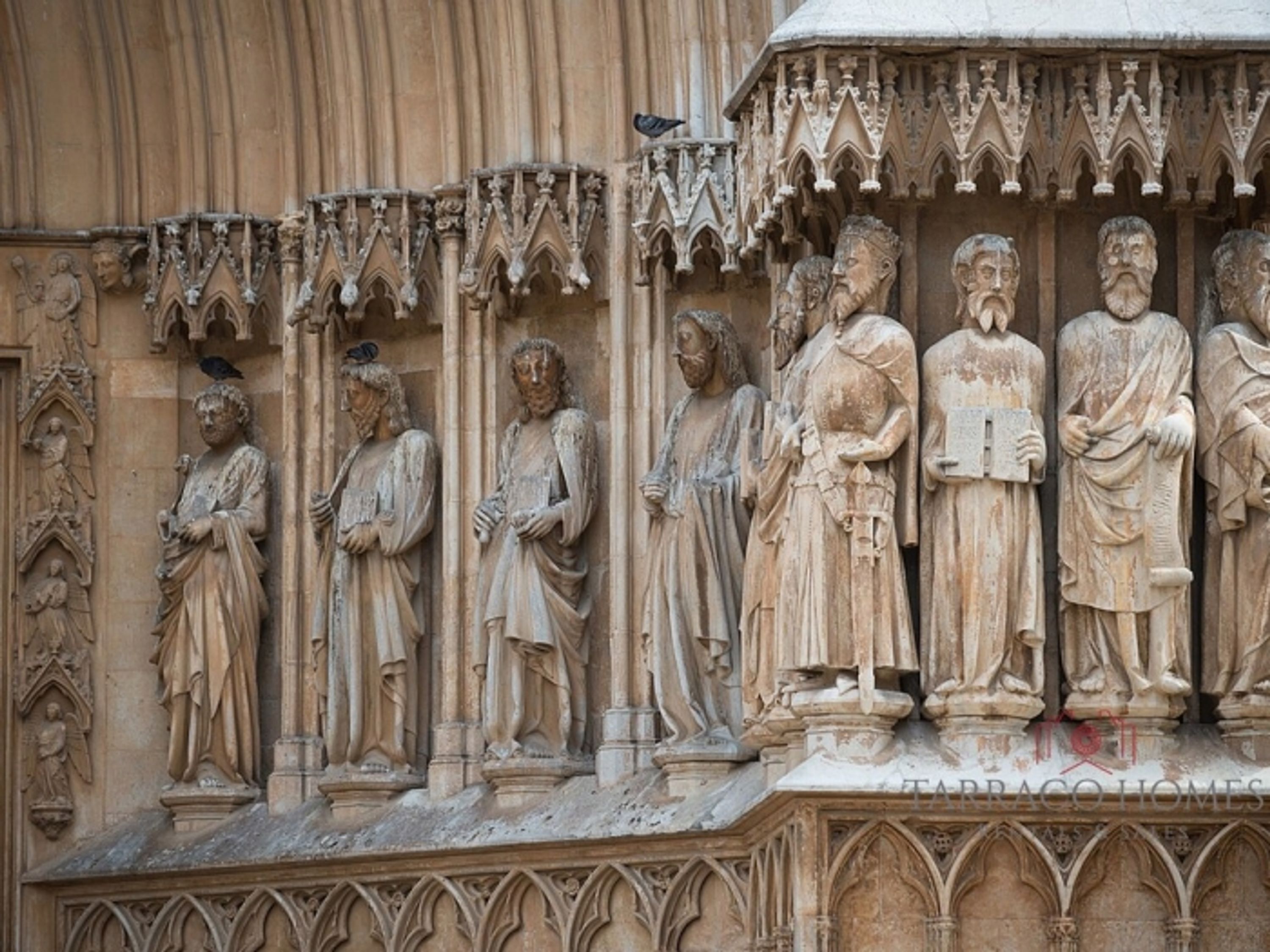 A detailed stone facade with Gothic architectural elements, including statues and intricate carvings.