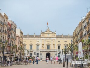 Historiallinen rakennus, jossa on keskeinen sisäänkäynti, ja sen ympärillä on kahviloita sekä ulkotiloja, joissa voi istua.