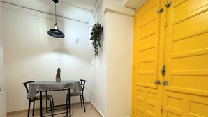 Un coin repas avec une table et des chaises, un luminaire suspendu et une porte jaune.
