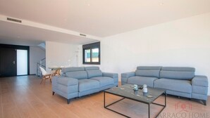Ein modernes Wohnzimmer mit zwei grauen Sofas, einem Glastisch und Holzböden.