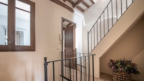 A staircase with a metal railing, a wooden door, and a woven basket with flowers. - Th125 Atico con Vistas en Tarrgona (Tarragona)
