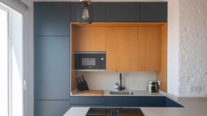Una cocina moderna con microondas integrado, un lavamanos y una encimera de madera.