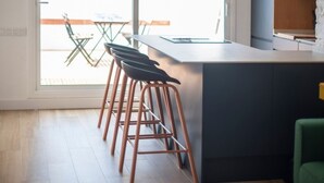 Una cocina moderna con una isla central, taburetes de bar y vistas al área exterior.
