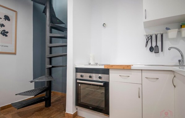 Eine moderne Küche mit weißen Schränken, einem eingebauten Backofen und einer Edelstahl-Dunstabzugshaube.