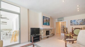 Una sala de estar con chimenea, televisor y comedor con sillas.
