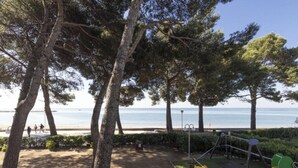 Un parque con árboles, un área de juegos y vistas a la playa.