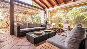 A covered patio area with a sofa, a coffee table, and a wooden table. - Th129 Villa Marinada en la Playa de Cambrils (Cambrils)