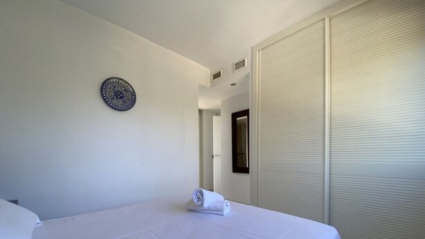A hotel room with a bed, a wall clock, and a closed sliding door. - Th26 Atico en Salou con Vistas y Piscina (Salou)