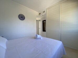 Hotellihuone, jossa on sänky, seinäkello ja suljettu liukuovi.