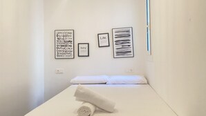 A minimalist bedroom with a bed, a wall-mounted light, and three framed artworks. - Th10 Apartamento Destral en el Centro de Tarragona (Tarragona)