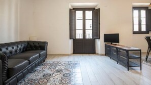 A spacious room with a black leather sofa, a small desk with a computer, and a patterned rug. - Th158 Aprtamento Sedassos (Tarragona)