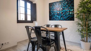 A dining area with a wooden table and black chairs, a large abstract painting on the wall, and a potted plant. - Th158 Aprtamento Sedassos (Tarragona)