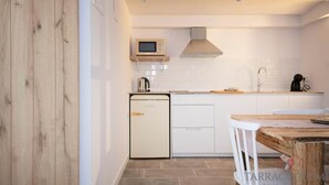 A compact kitchen with white cabinetry, a microwave, a kettle, and a sink. - Th56a Apartamentos Murmur la Font (Tarragona)
