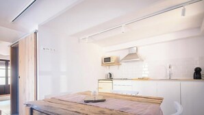 A modern kitchen with white cabinets, a wooden table, and a microwave. - Th56a Apartamentos Murmur la Font (Tarragona)