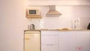 Ett modernt kök med vita skåp, en inbyggd mikrovågsugn, en vattenkokare i rostfritt stål och en diskho.