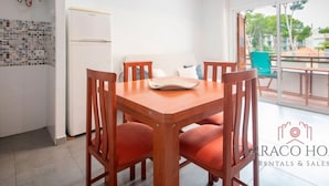 A modern kitchen with a white refrigerator, a tiled backsplash, and a dining area with a wooden table and four chairs.