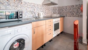 A compact kitchen with a washing machine, a microwave, a sink, and a stove.