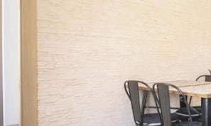 A corner of a room with a textured wall and a table with chairs. - Th134 Apartamento Moderno Centro de Tarragona (Tarragona)