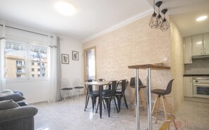 Een modern appartement met een eethoek, keuken en uitzicht op gebouwen.