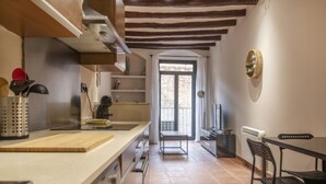 A modern kitchen with a wooden ceiling, a dining area with a table and chairs, and a view through a doorway to an outdoor balcony. - Th86 Apartamento con Encanto en Parte Alta (Tarragona)