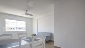 A spacious living room with a dining table, chairs, a sofa, and a ceiling fan. - Th64 Apartamento Moderno Cerca de la Universidad (Tarragona)