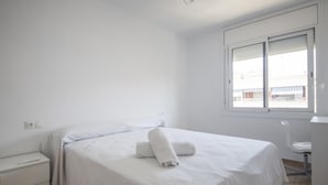 A minimalist hotel room with a single bed, a bedside table, and a window with a view of the outside. - Th64 Apartamento Moderno Cerca de la Universidad (Tarragona)