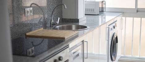 A modern kitchen with a granite countertop, stainless steel sink, and built-in appliances including a dishwasher and oven.