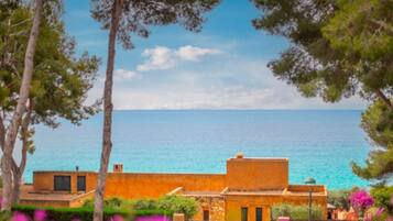 A coastal property with a view of the sea, featuring a building with a flat roof and a small balcony.