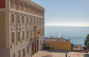 Un immeuble doté d’un grand balcon donnant sur la mer, orné d’un drapeau et d’une fontaine.