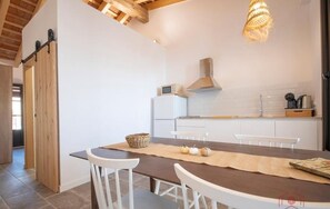 Una cocina moderna con armarios blancos, una mesa de comedor de madera y una lámpara colgante.