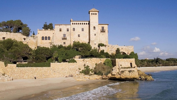 Un bâtiment historique en pierre, doté d’une tour, situé sur une falaise côtière surplombant la mer.