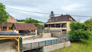 A rustic building with a stone facade, a wooden deck, and a small outdoor seating area. - Charming House in the Heart of the Périgord Noir – Private Pool & Preserved Nature (Siorac-en-Périgord)