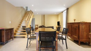 A dining area with a wooden table and chairs, a staircase, and a wooden cabinet. - Charming House in the Heart of the Périgord Noir – Private Pool & Preserved Nature (Siorac-en-Périgord)