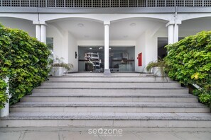 Un escalier en pierre menant à l’entrée d’un bâtiment, avec des colonnes blanches et des portes en verre.