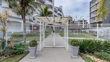 A gated entrance to a residential complex with a covered walkway, palm trees, and a white fence.