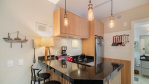 Una cocina moderna con una isla central, armarios de madera e iluminación colgante.