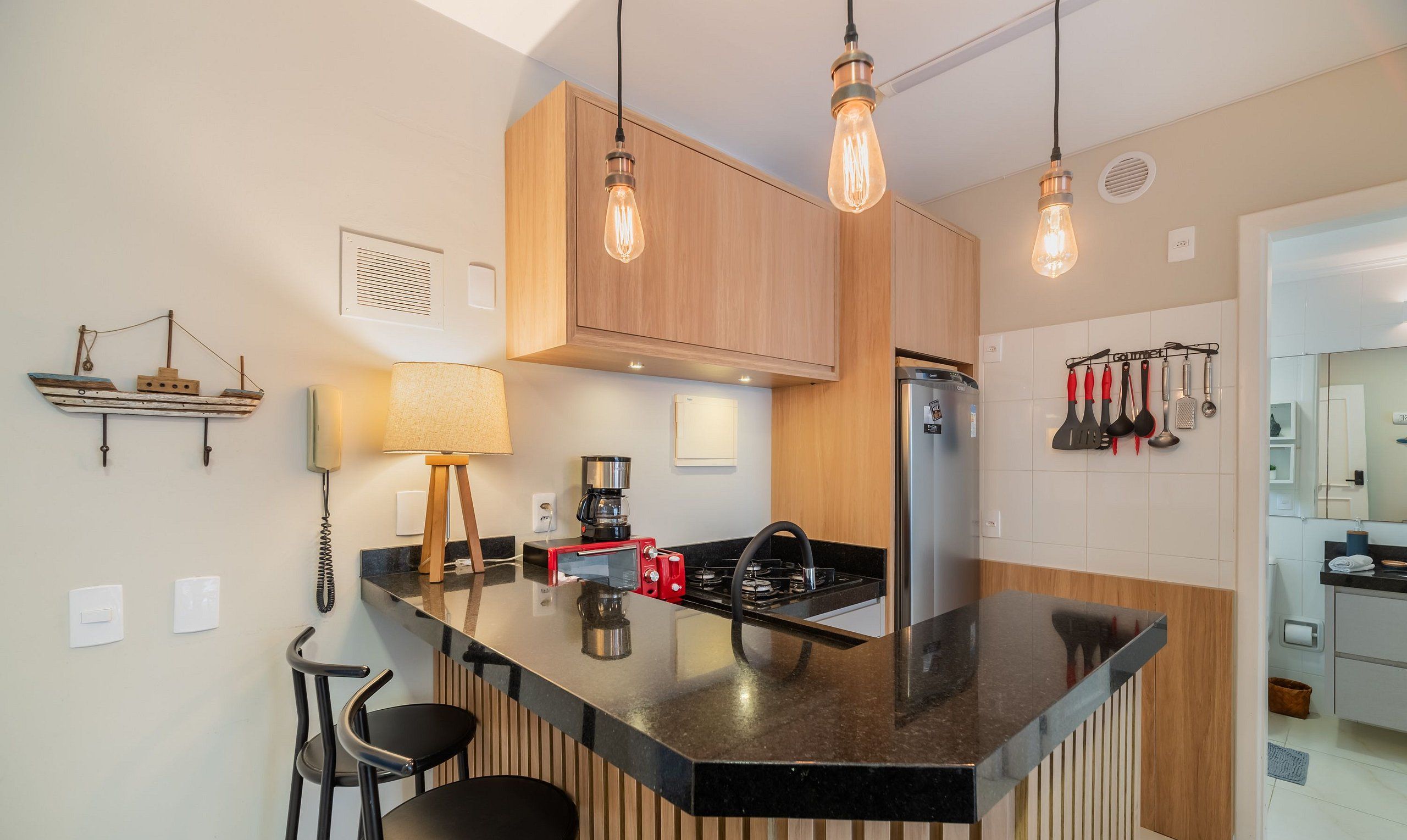 A modern kitchen with a central island, wooden cabinets, and pendant lighting.