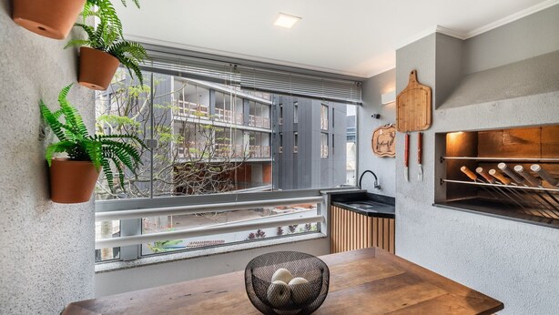 Una cocina moderna con un amplio ventanal, una mesa de comedor de madera y plantas en macetas.