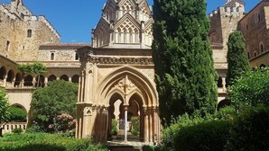 A historic building with a Gothic entrance, surrounded by lush greenery and a clear blue sky. - CASA RURAL AMANECER (Castañar de Ibor)