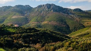 A mountainous landscape with a small building on a hillside. - CASA RURAL AMANECER (Castañar de Ibor)