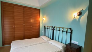 A bedroom with a bed, wooden wardrobe, and wall-mounted light fixtures.
