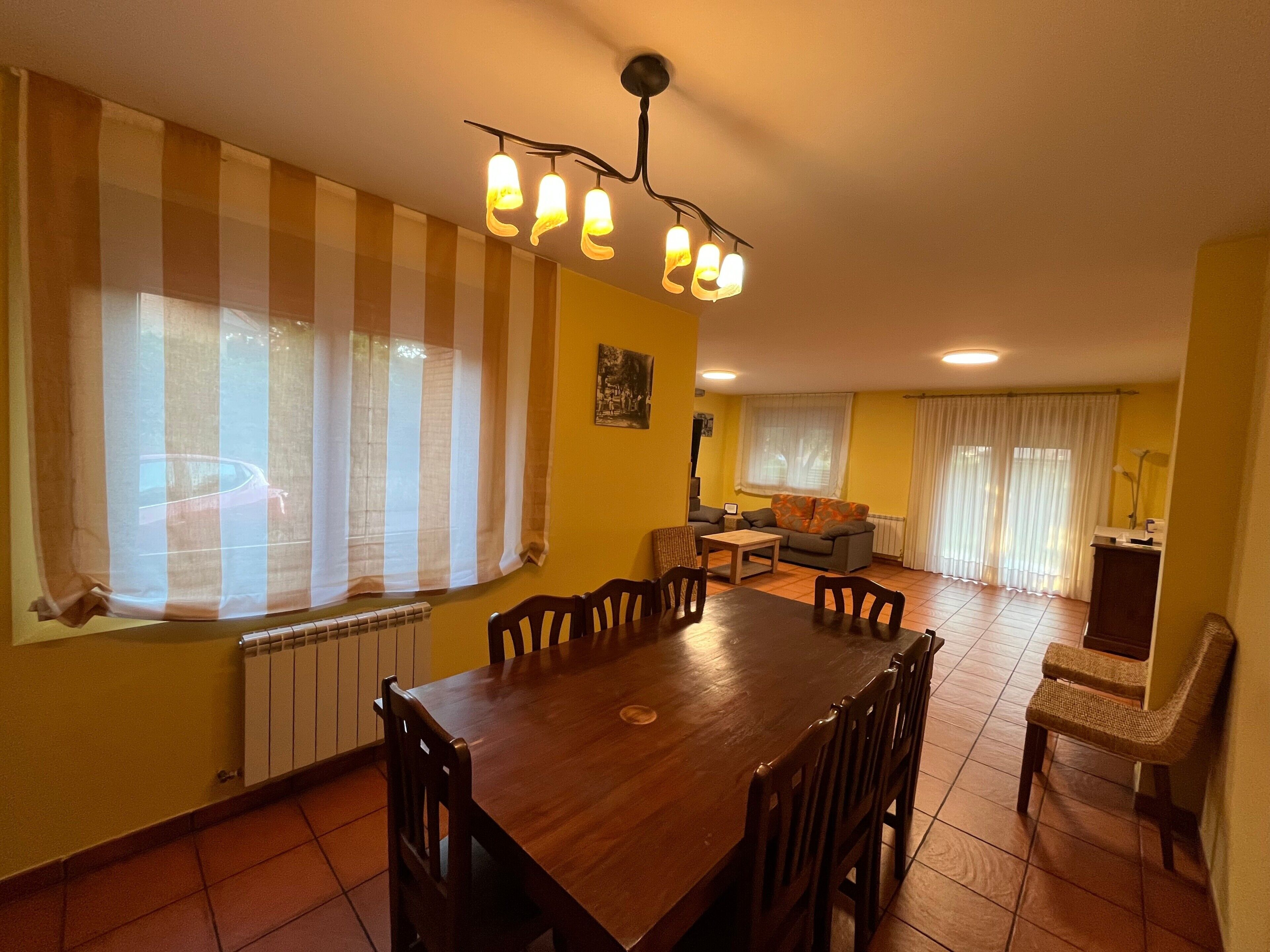Un coin repas avec une table et des chaises en bois, un radiateur et une fenêtre ornée de rideaux à rayures.