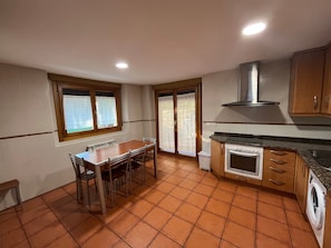 A kitchen with a dining table, chairs, a washing machine, and a stove.