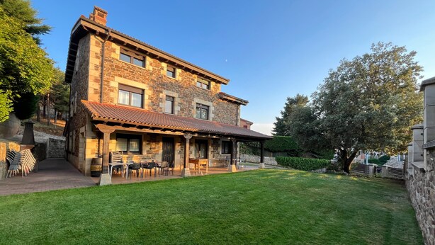 A stone building with a tiled roof, outdoor seating, and a well-maintained lawn.