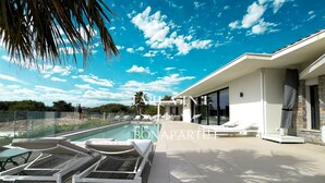 Une maison moderne dotée d’une piscine, de chaises longues et d’un espace patio.